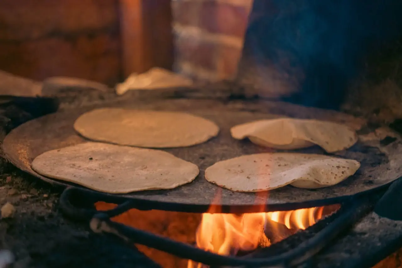 Hands rolling corn tortillas on a wooden board at a Cancun cooking class