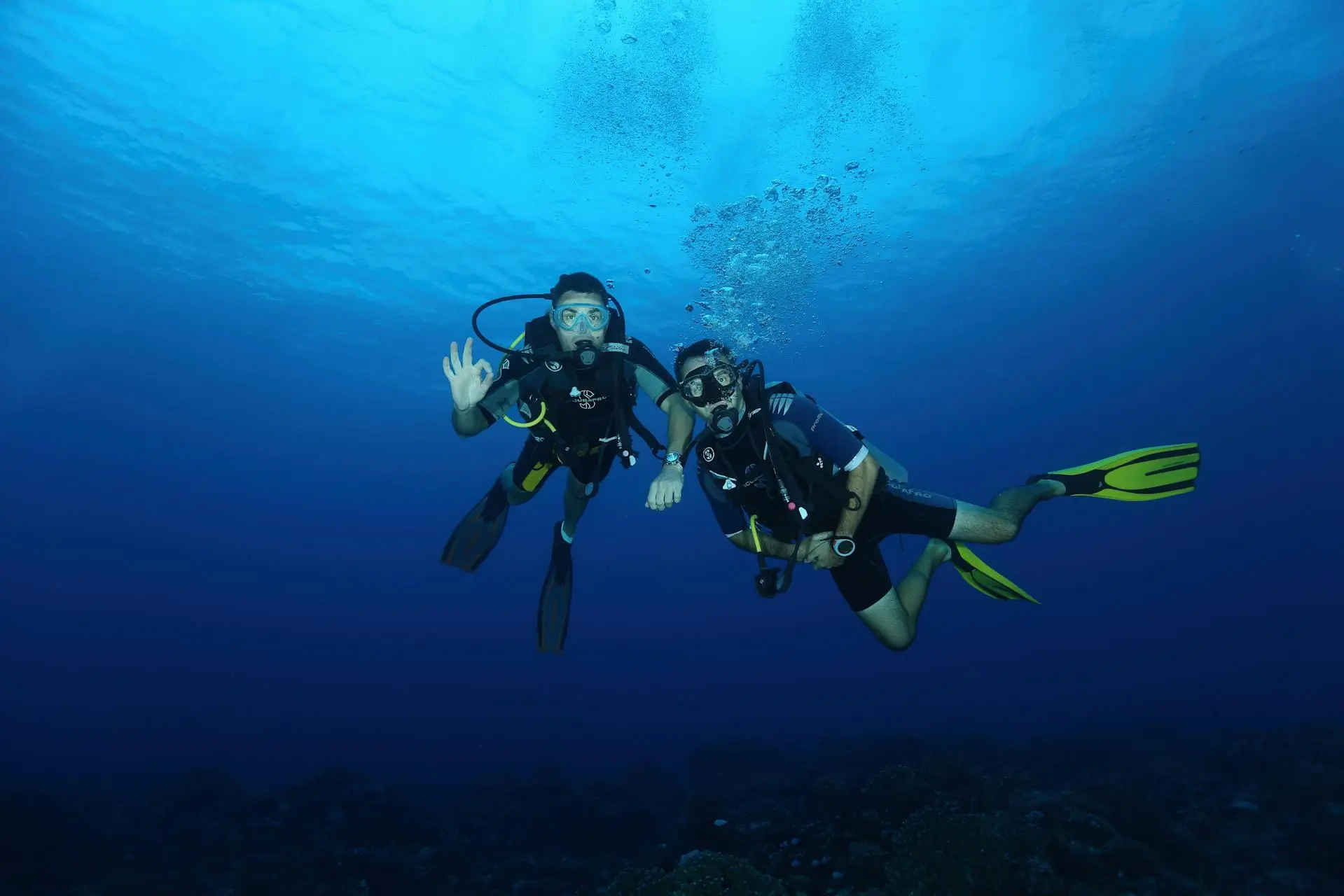 Principiante de buceo descendiendo junto a un instructor sobre un arrecife de coral en Cancún, México