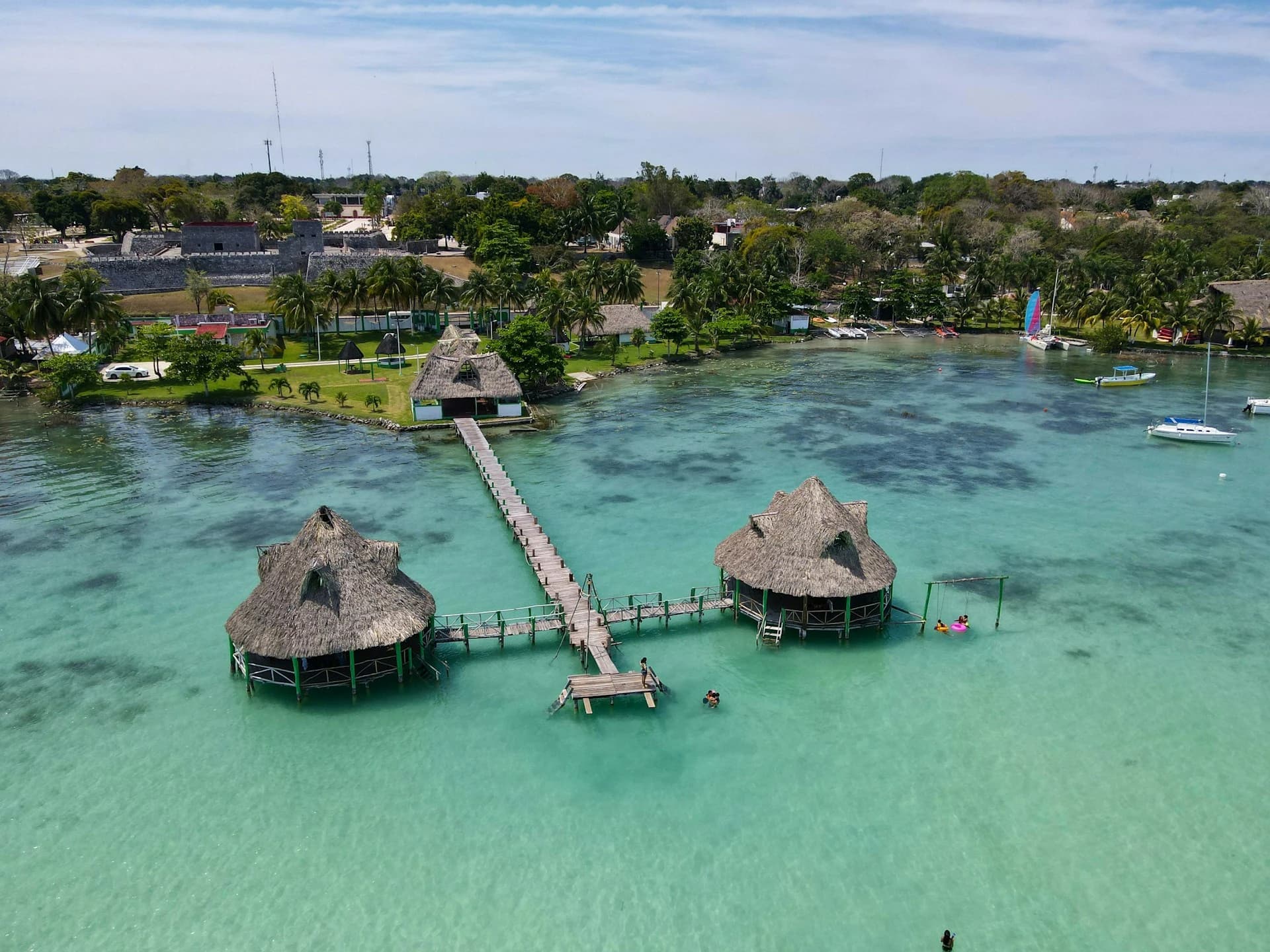 Sailboat on Bacalar Lagoon under breaking storm clouds with turquoise shallows in October