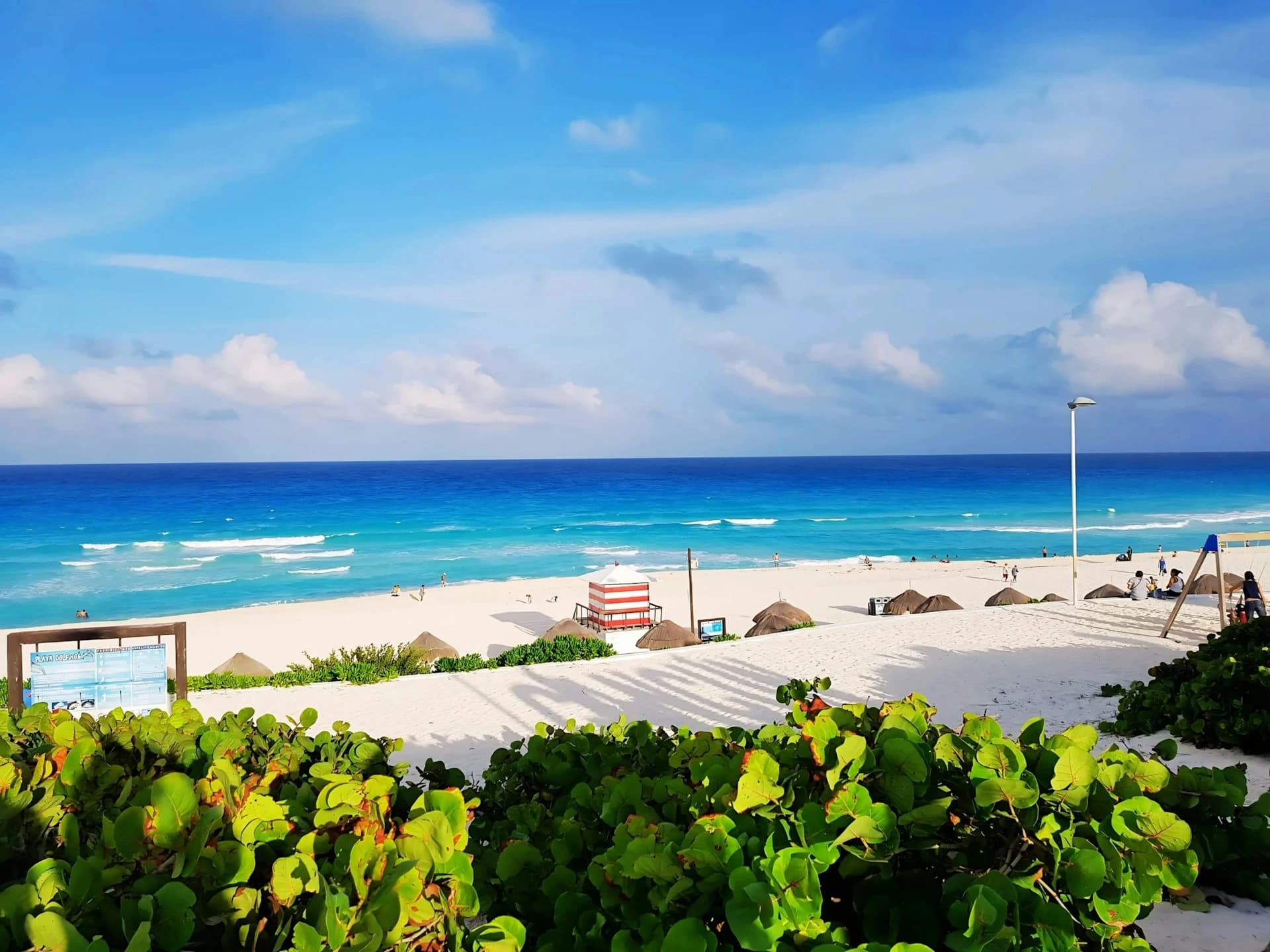 Loungers and palapas on the sand in front of a beachfront resort on Cancún's calm bay shore