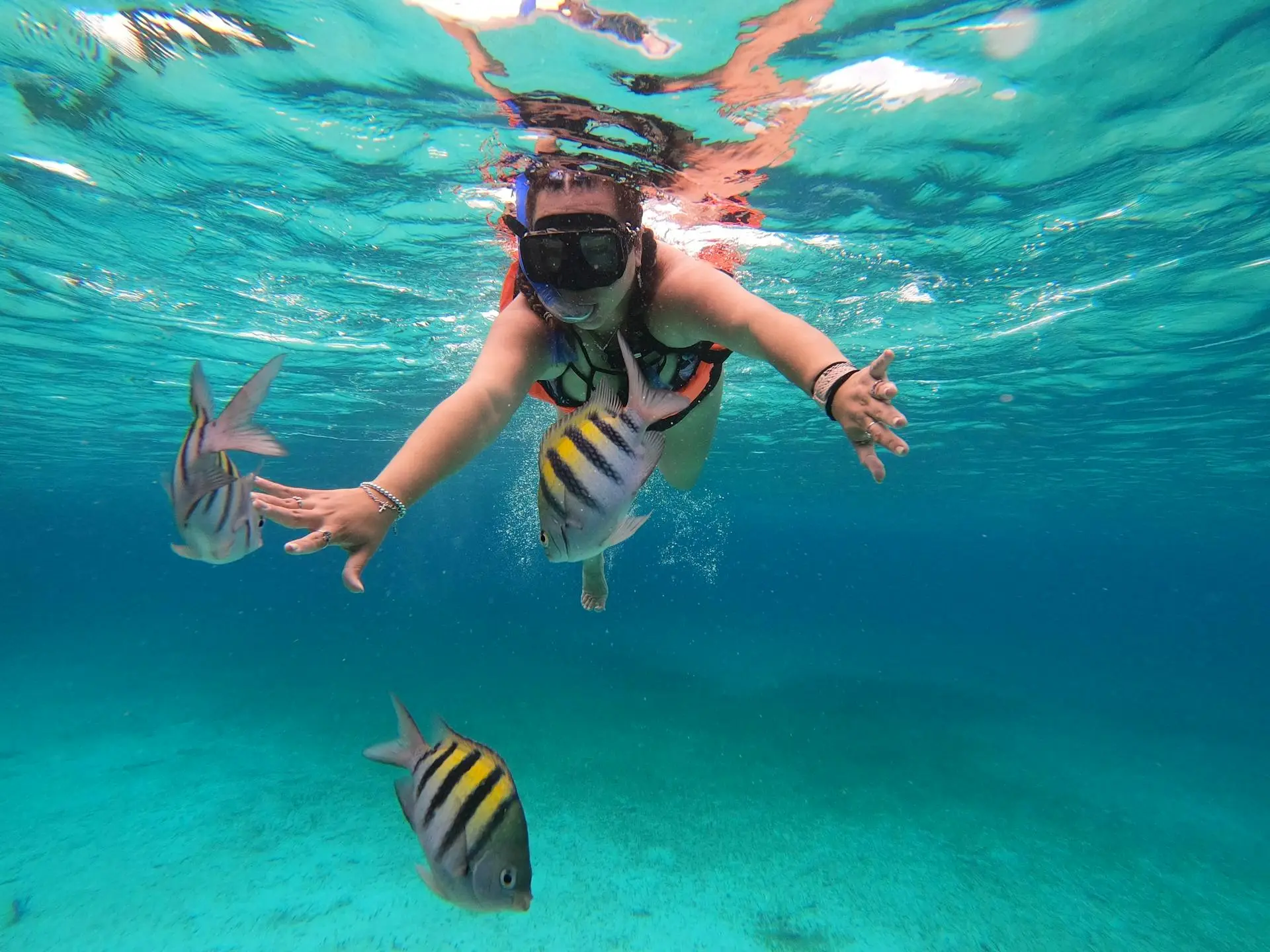 Snorkeler swimming above a coral reef in clear turquoise water near Isla Mujeres, Mexico