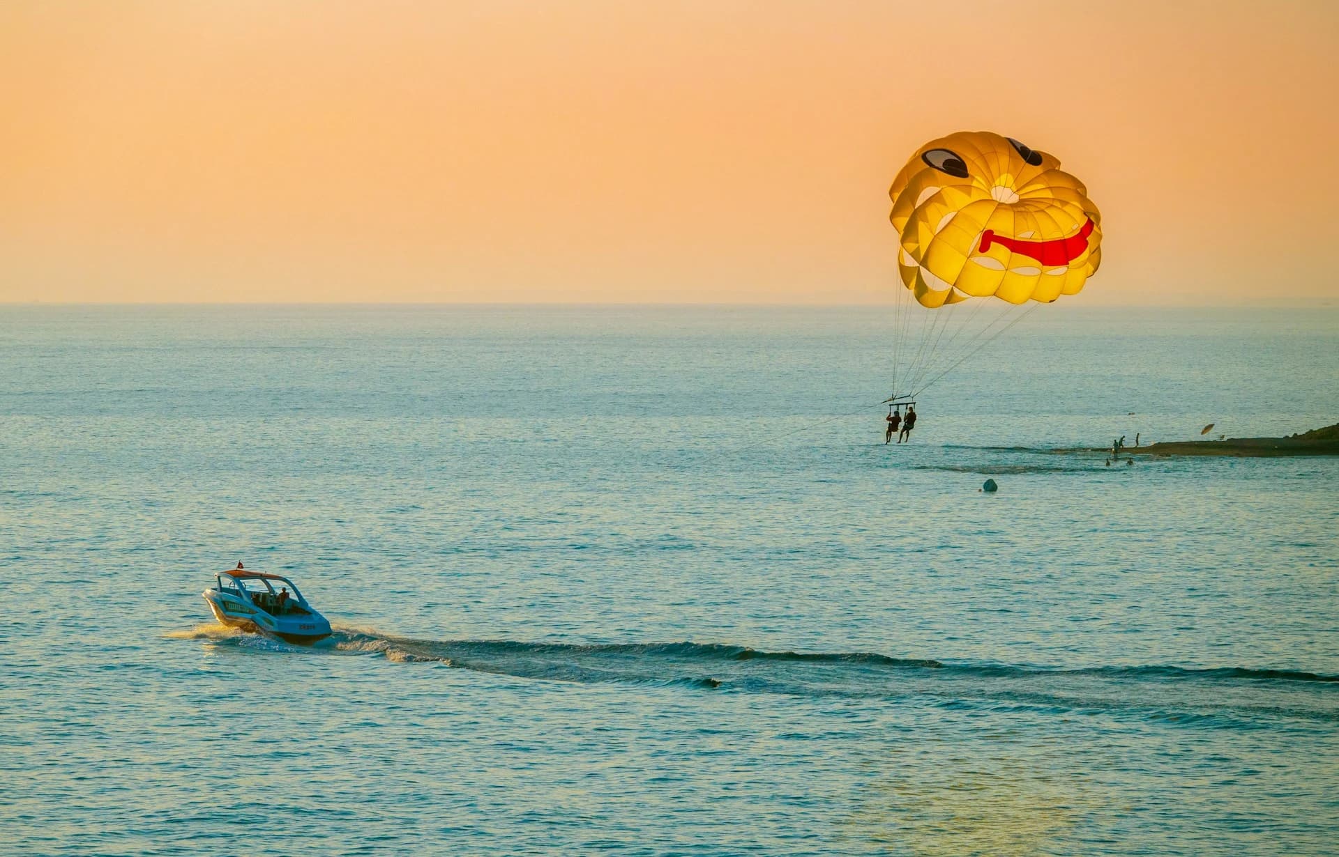Parasail canopy lifting two riders high above the turquoise Caribbean off Cozumel
