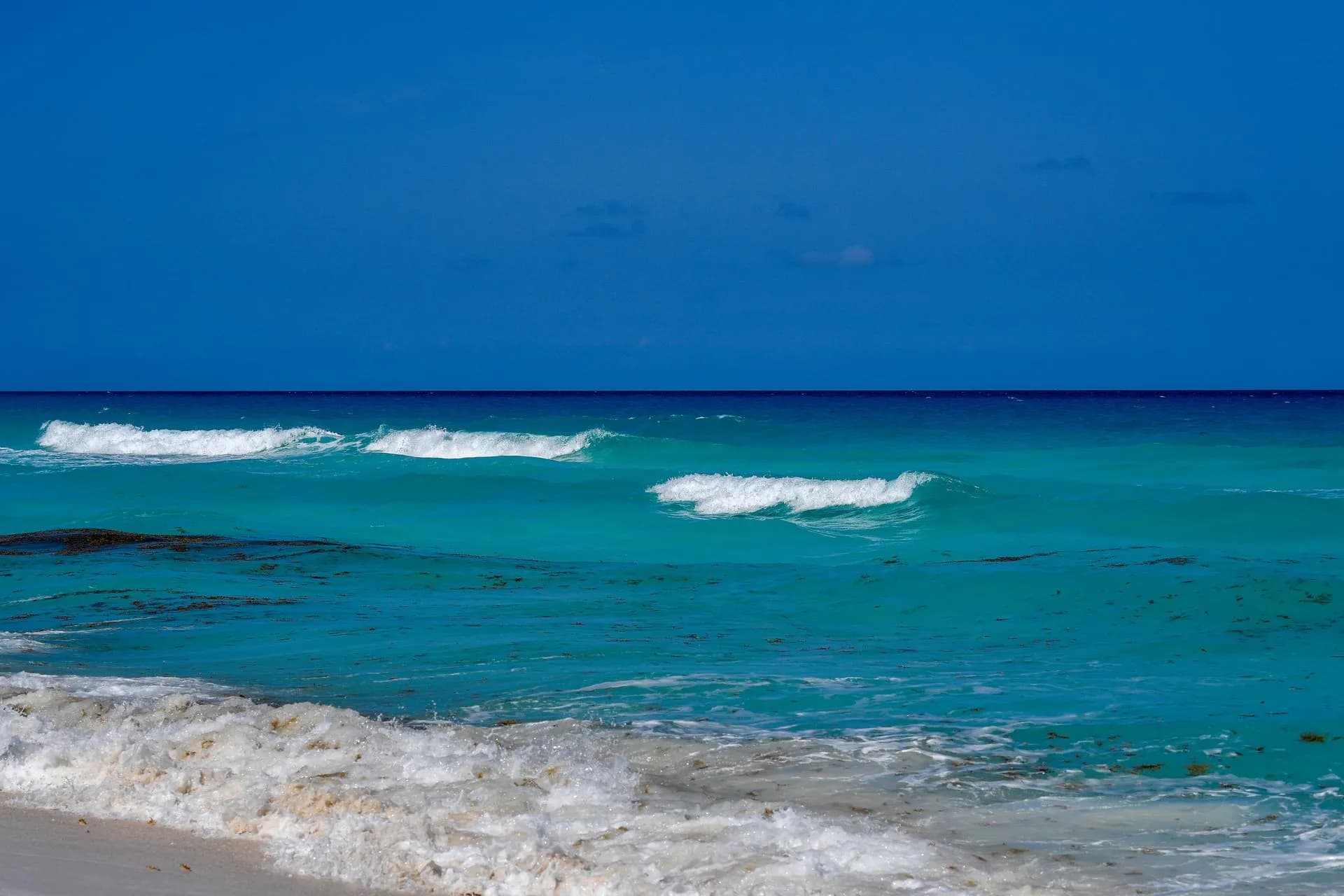 Calm turquoise water and white sand at Playa Caracol on Punta Cancún, with the Isla Mujeres ferry pier beside the beach