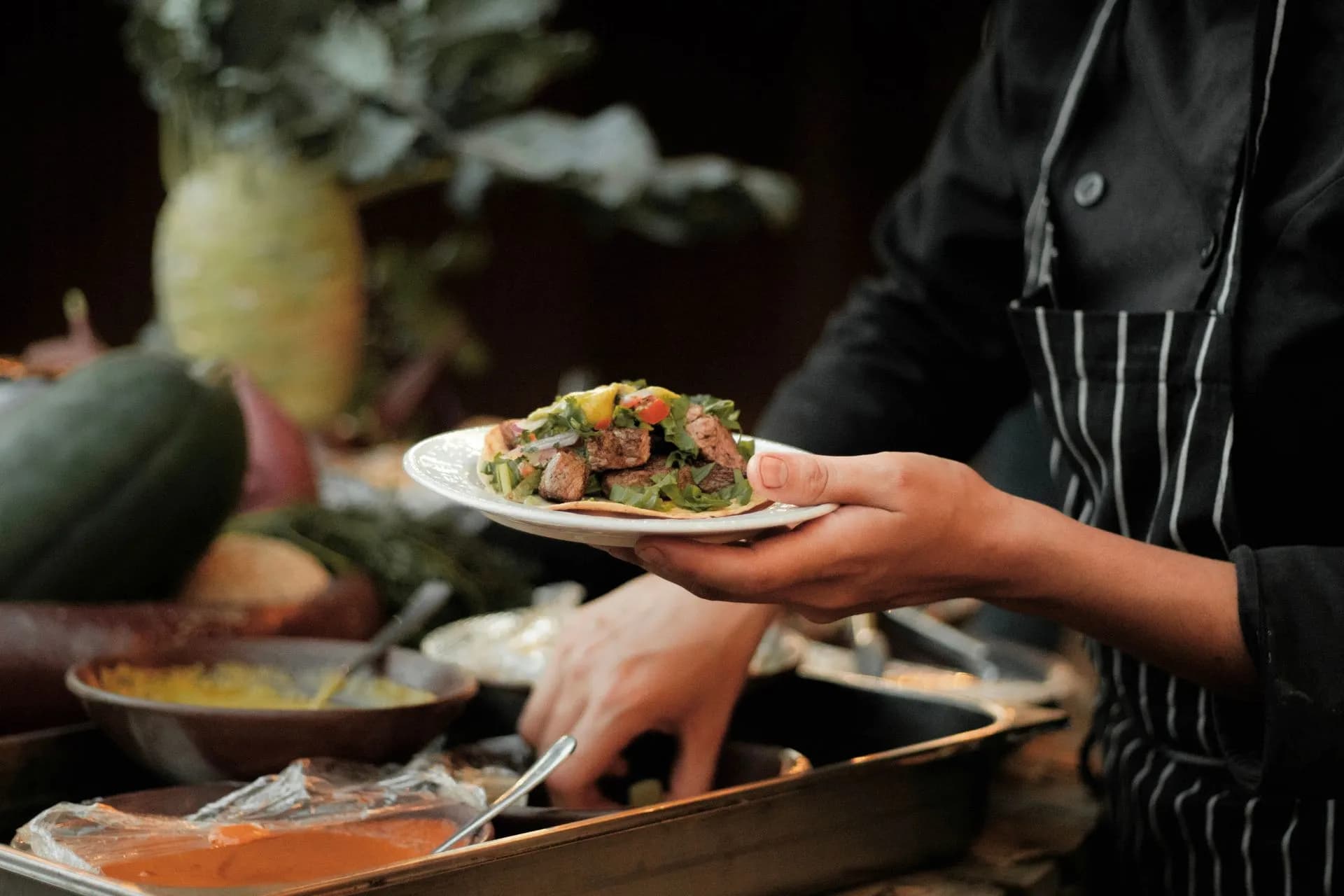Private chef plating a multi-course Mexican dinner in a Tulum villa kitchen for a small group