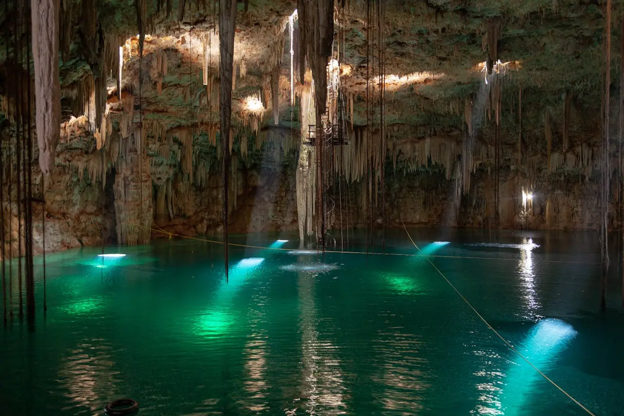 Grupo guiado caminando entre formaciones de estalactitas luminosas dentro de Rio Secreto, México